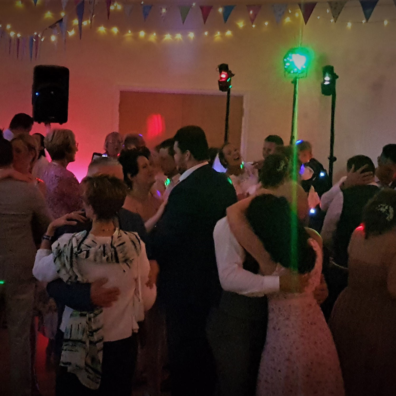 Multiple couples in smart clothes sway and embrace during romantic dance at wedding near Bristol in front of Jon Paul DJ and lighting.