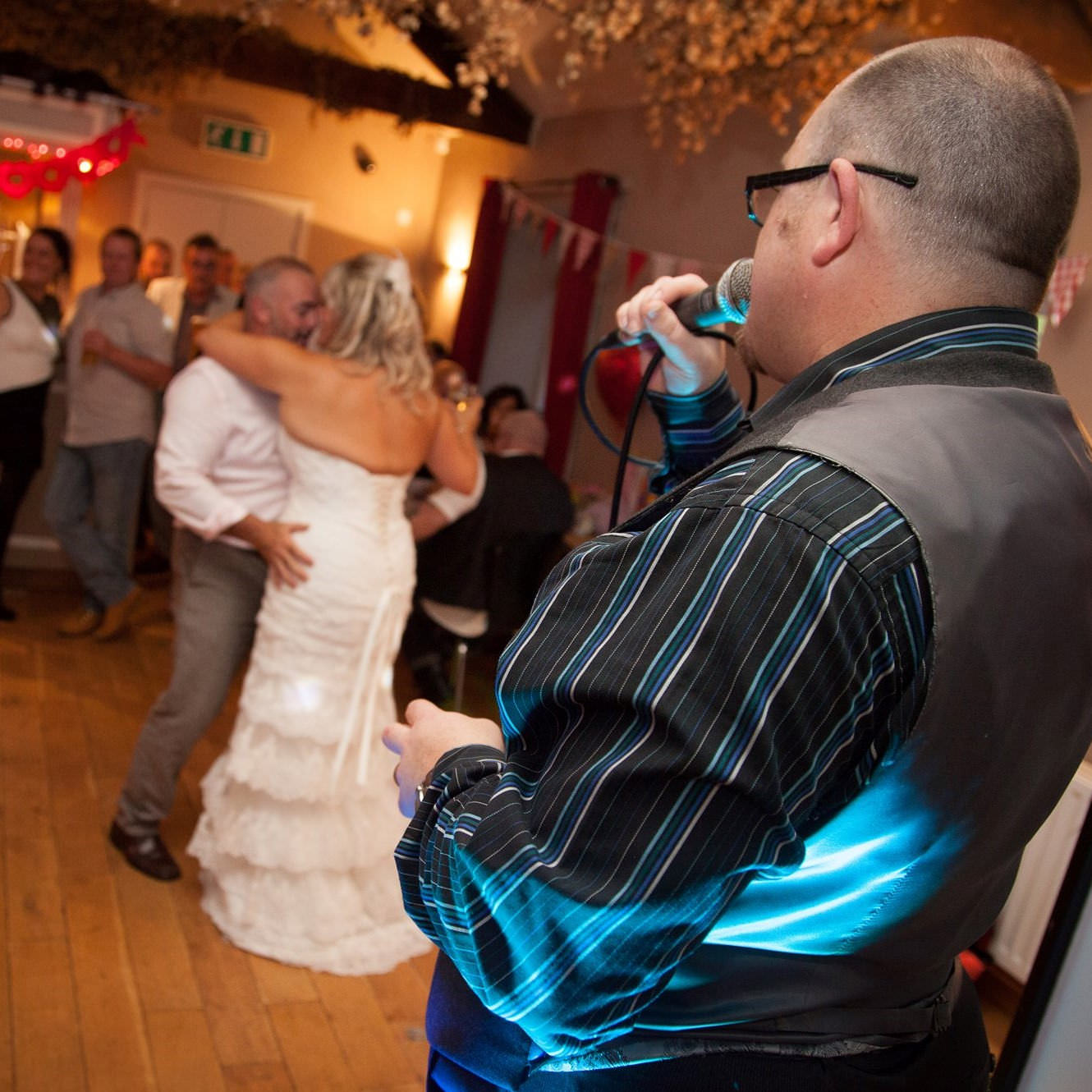 Jon Paul singer sings from stage to newlywed pair embraced in first dance at wedding reception near Bristol.